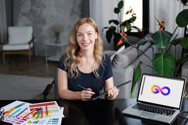 Foto designer de logotipo trabalhando em seu tablet conectado a um laptop