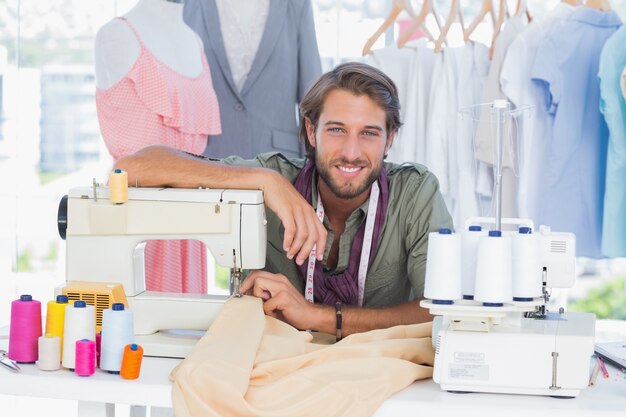 Designer de moda apoiado na máquina de costura