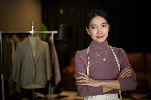 Designer de moda asiática de sucesso ou alfaiate fica com os braços cruzados em seu estúdio