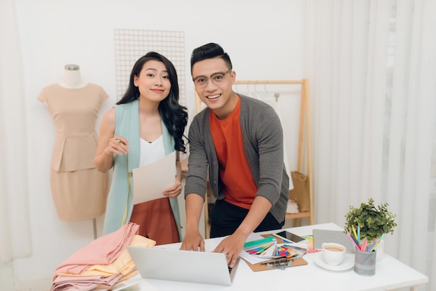 Designer de moda jovem feliz e homem trabalhando na oficina