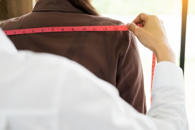 Designer de moda que mede no corpo parte das mulheres para um vestido feito sob medida para uma jovem empresa de negócios