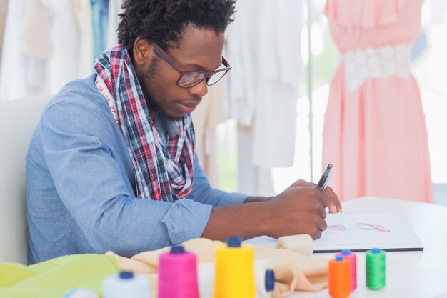 Designer de moda sentado em seu desenho de mesa