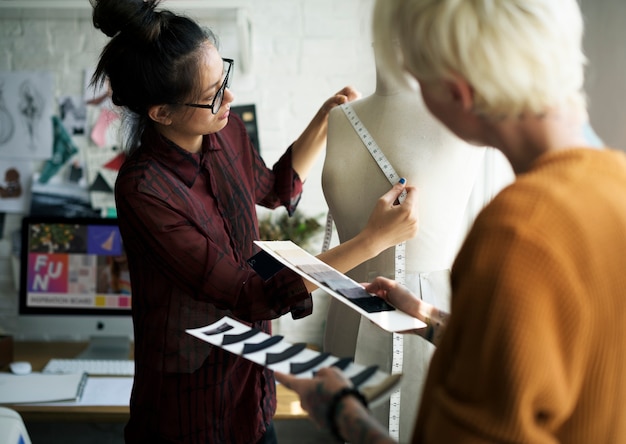 Designer de moda usando uma fita métrica em um manequim