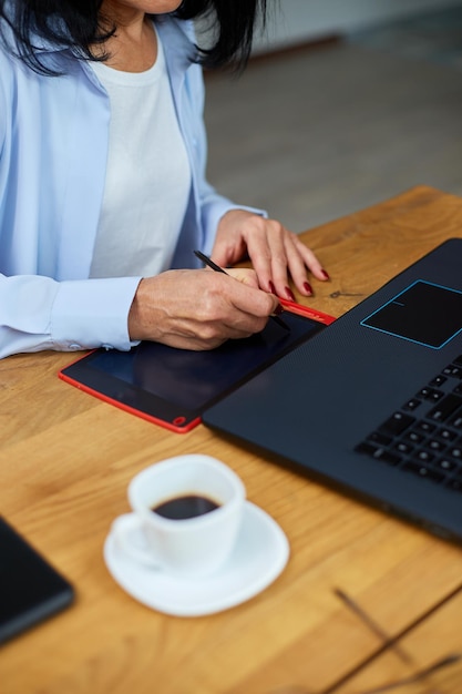 Designer de mulher madura usando mesa digitalizadora e caneta