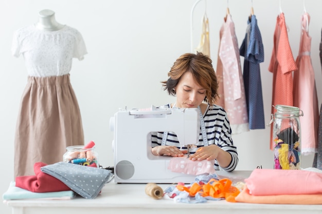 Designer de roupas, costureira, conceito de pessoas - costureira trabalhando em seu estúdio