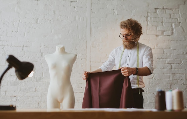 designer de roupas jovem moderno no processo de trabalho, um designer de roupas com cabelo comprido e barba