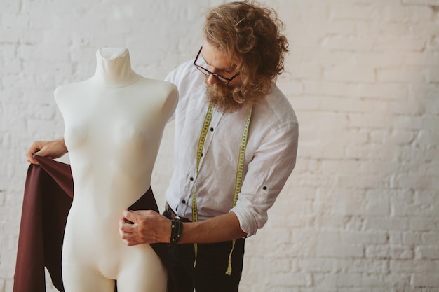 designer de roupas jovem moderno no processo de trabalho, um designer de roupas com cabelo comprido e barba