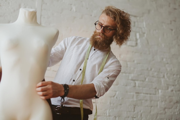 designer de roupas jovem moderno no processo de trabalho, um designer de roupas com cabelo comprido e barba