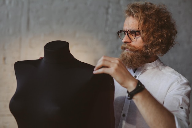 designer de roupas jovem moderno no processo de trabalho, um designer de roupas com cabelo comprido e barba