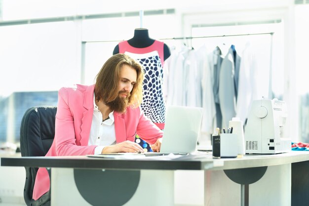 Designer de sucesso trabalha em um laptop sentado em seu estúdio