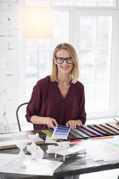 Designer em ação. Alegre estilista sorrindo para a câmera enquanto pega a cor