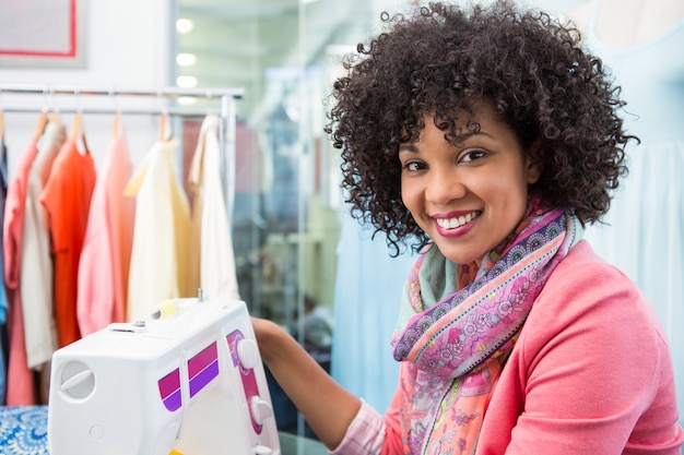 Designer feminino de moda usando máquina de costura