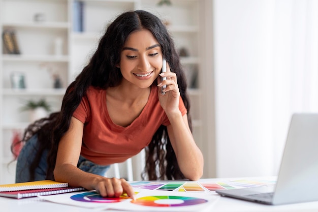 Designer freelancer de mulher trabalhando com laptop e celular em casa