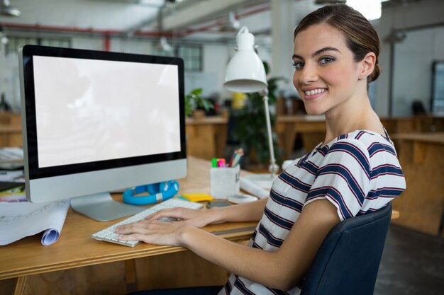 Designer gráfica feminina sorridente trabalhando no computador