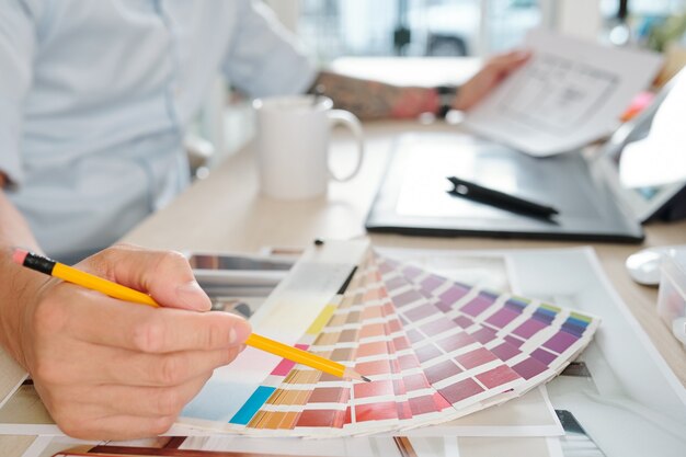 Designer gráfico escolhendo a cor na paleta ao trabalhar no projeto para o cliente