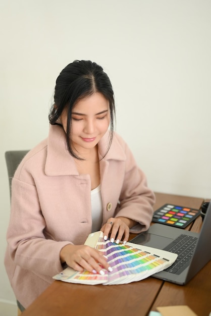 Designer gráfico feminino profissional trabalhando em sua mesa de escritório olhando amostras de amostras de cores