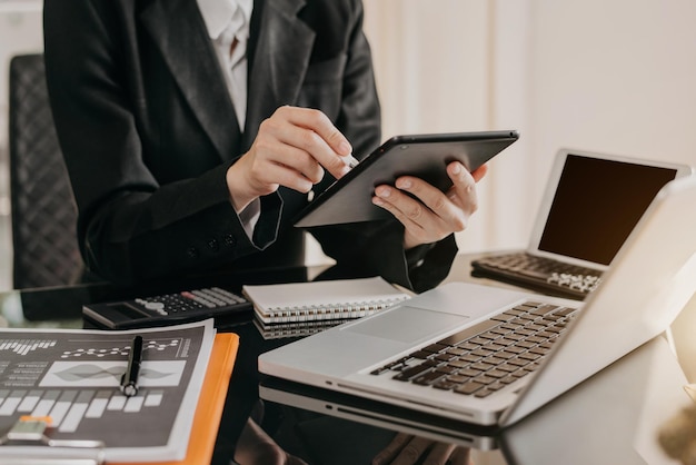 Designer mit Tablet mit Laptop und Diagramm auf dem Schreibtisch im modernen Büro.