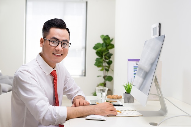Designer sorridente trabalhando em sua mesa em um escritório moderno