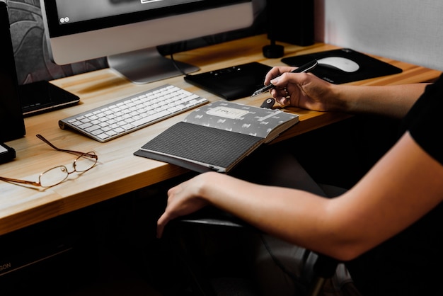 Designermädchen bei der Arbeit am Tisch zeichnet auf dem Tablet, schließt die Tastatur, den Drucker, den Computer