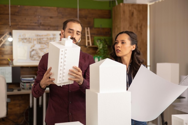 Designers criativos e arquitetos trabalhando com modelos 3D em escritórios modernos