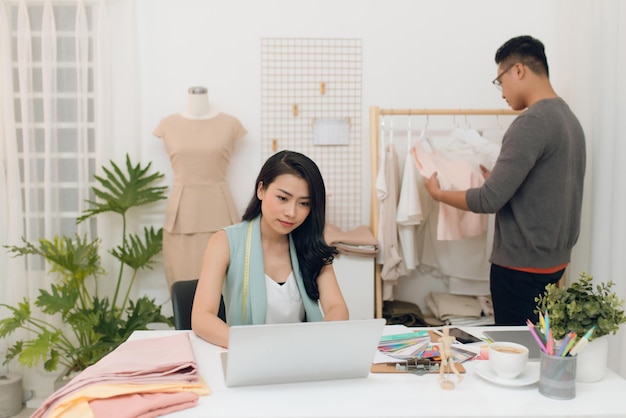 Designers de moda no trabalho Designer masculino bonito escolhendo design enquanto seu colega trabalhando com laptop