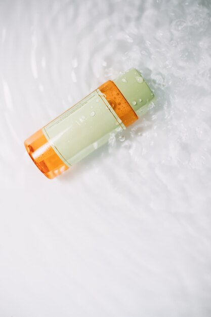 Designkonzept der Kosmetikverpackung, Modell mit leerer transparenter Flasche auf einer weißen Wasseroberfläche