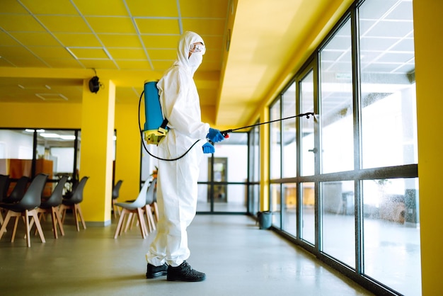 Desinfecção de escritório para prevenir covid-19, homem em traje de proteção anti-risco. conceito de limpeza.