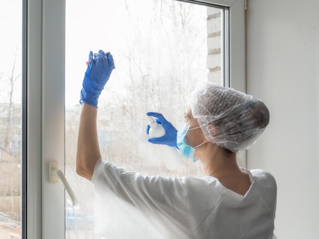 Foto desinfecção por coronavírus. pessoas em fazer desinfecção no windows. doutor em luvas de borracha desinfeta janelas com desinfetante e esponjas