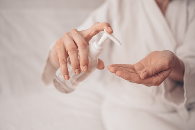 Desinfectante de manos mujer aplicando alcohol desinfectante gel gel líquido frotando manos femeninas higiene personal higiene coronavirus pervención en casa. Botella desinfectante. Detener el concepto COVID19