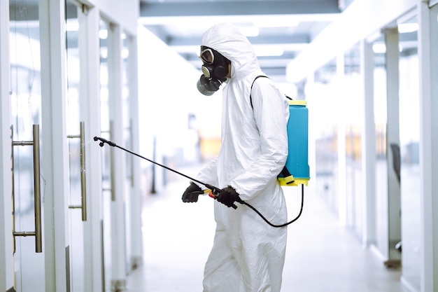 Desinfektion des Büros zur Vorbeugung von COVID-19, Mann im Schutzanzug mit Sprühchemikalien.