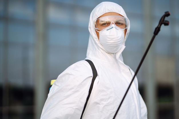 Desinfektion zur Vorbeugung von COVID-19, Mann im Schutzanzug mit Spray.