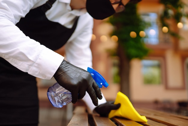 Foto desinfetando para prevenir covid19 garçom limpando a mesa com spray desinfetante