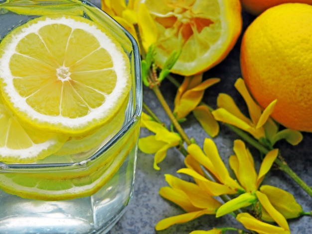 Desintoxica el agua con jugo de limón y flores amarillas en las ramas.