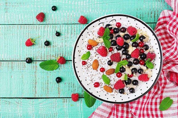 Desintoxicación y súper alimentos saludables desayuno en un tazón. Pudín de semillas de chía con leche de almendras veganas con frambuesas, moras y menta. Vista superior. Lay Flat