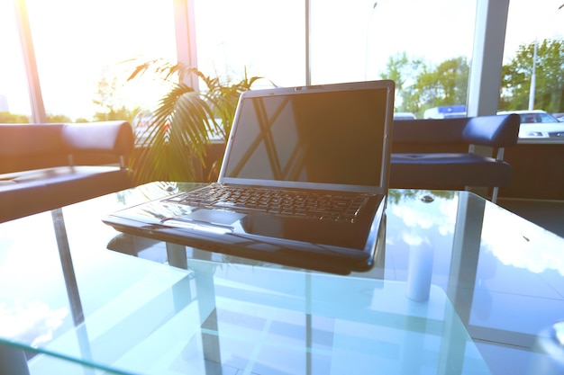 Desktop Desktop moderno com um laptop no escritório em uma mesa de vidro, tela em branco.