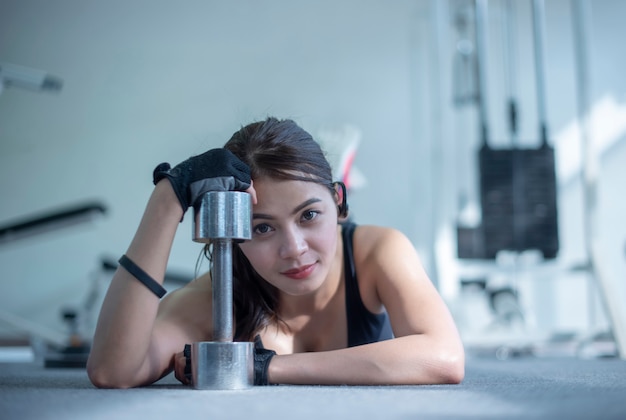 Foto deslice la vista de la mujer de la aptitud que ejercita con la elevación la pesa de gimnasia en gimnasio.