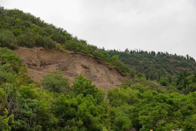Un deslizamiento de tierra de montaña en una zona ecológicamente peligrosa, la caída de grandes capas de tierra bloqueando la carretera. Suelo en condiciones de erosión.