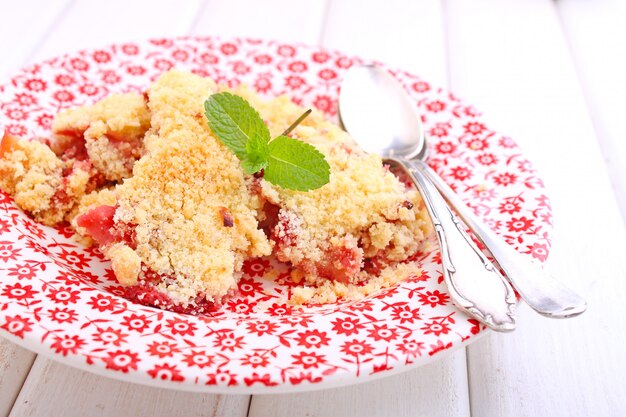 Desmenuzar con fresas en plato blanco sobre un fondo azul