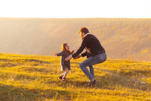 Desocupação da família. Foto do pai pegando sua filha, prado ou parque no pôr do sol