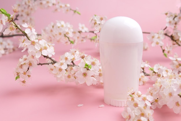 Desodorante branco em fundo rosa com cereja florescendo