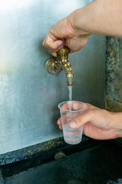 Despejando água termal mineral no copo descartável na sala de bombas