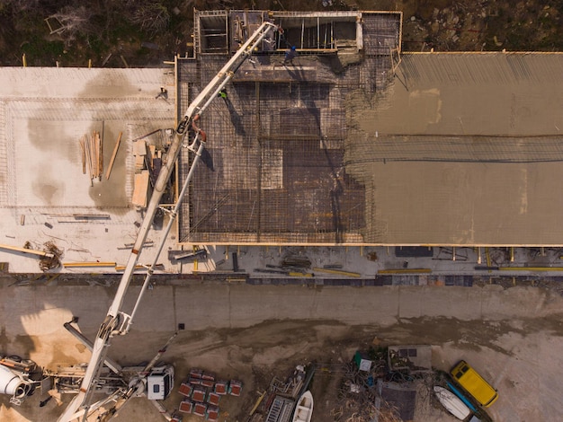 Despejando cimento de concreto no telhado de edifício residencial em construção usando uma máquina de caminhão bomba de concreto com lança alta para fornecer a mistura para os andares superiores Vista aérea