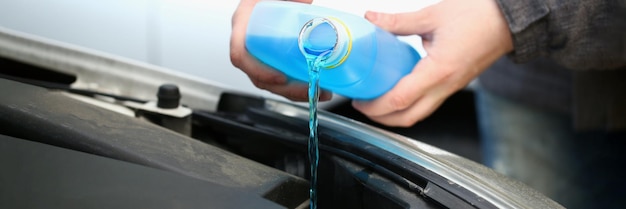 Despejando líquido anticongelante azul para lavar vidros de carros de perto