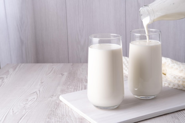 Despejar leite de manteiga de kefir ou iogurte caseiro com iogurte probiótico que flui de uma garrafa de vidro