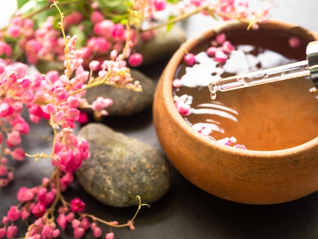 Despeje à mão óleo de coco no aroma essencial de flores rosas com seixos zenóleo de massagemaromaterapia spa conjunto para hotel de banheiro de luxo ou massagem profissional aromática oriental para a saúde