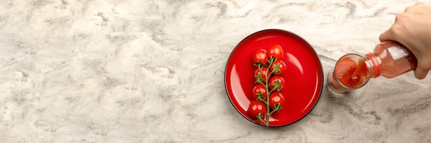 Despeje o suco de tomate em um copo. Mão derrama suco de tomate da garrafa em vidro, fundo de mesa de mármore. Espaço de cópia de banner