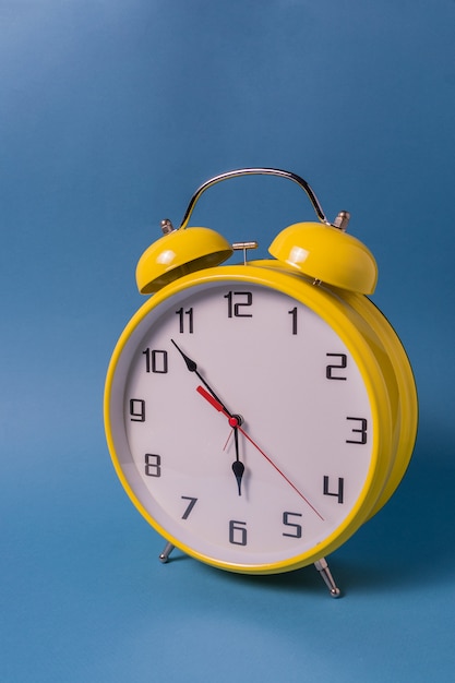Despertador amarelo do estilo retro com sete minutos a seis horas.