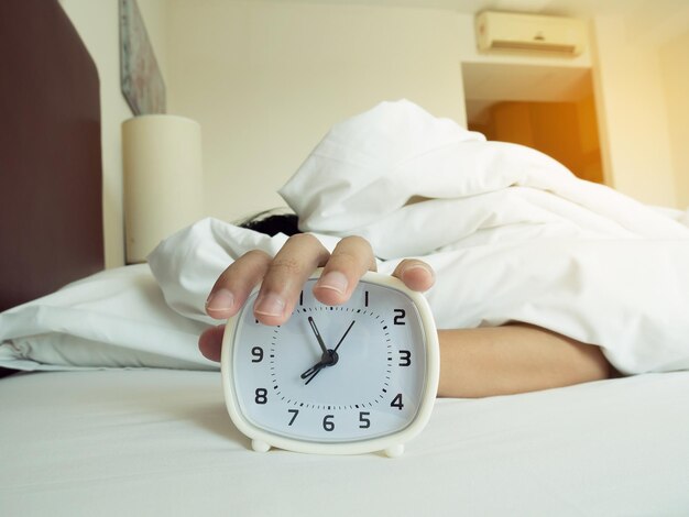 Foto despertador blanco y hombre dormido