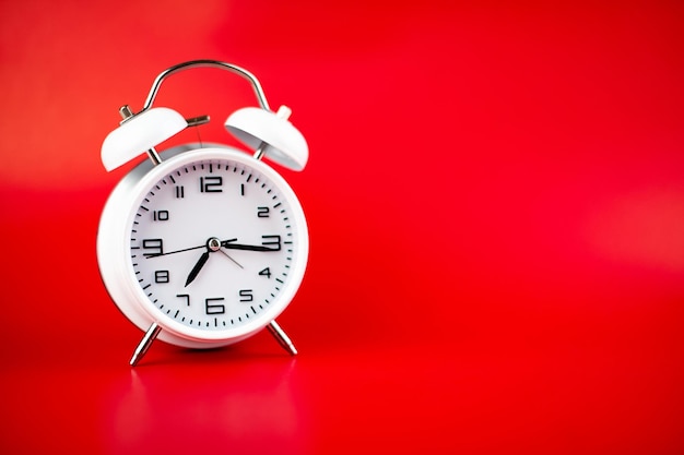 Foto despertador blanco sobre fondo rojo concepto de tiempo