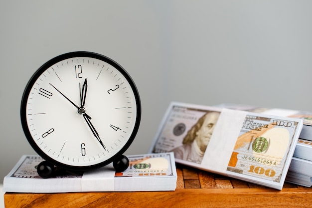 Despertador branco colocado em dólar de prata e conceito de finanças simplificado no tempo